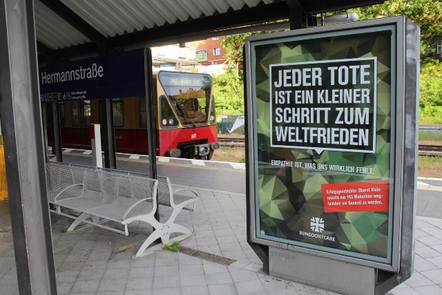 Austauschbare Werbetafel auf dem S-Bahnhof Neukölln mit persiflierter Bundeswehr-Werbung und dem Spruch: Jeder Tote ist ein kleiner Schritt zum Weltfrieden.